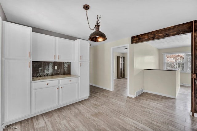 kitchen featuring beamed ceiling, decorative backsplash, light wood-type flooring, and white cabinetry