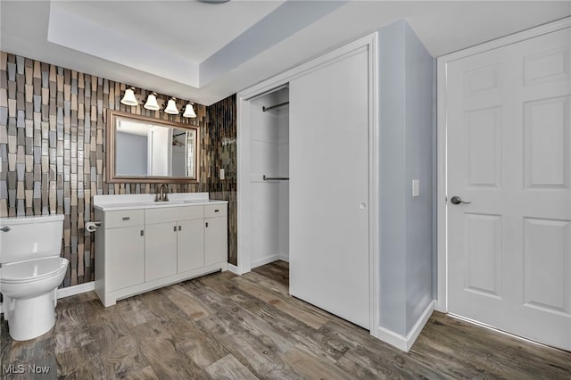 bathroom with hardwood / wood-style floors, vanity, tile walls, and toilet