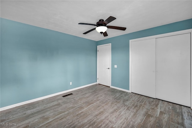 unfurnished bedroom with wood-type flooring, a closet, and ceiling fan