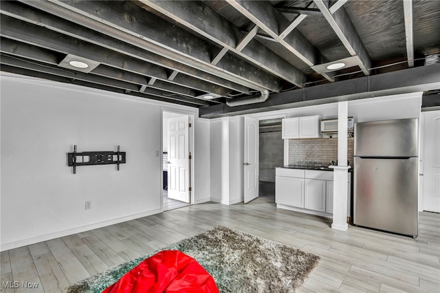 basement featuring stainless steel fridge and light wood-type flooring