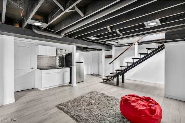 basement with stainless steel refrigerator, light hardwood / wood-style floors, and wet bar