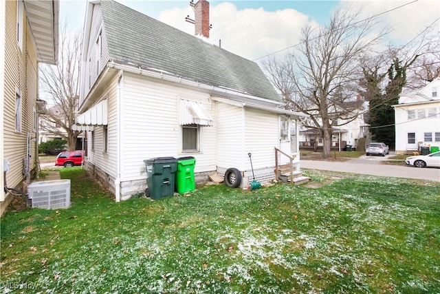 view of side of home featuring a lawn and central AC