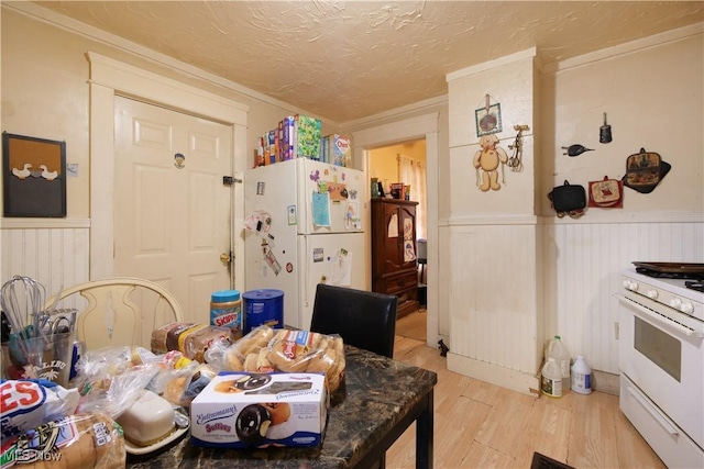 kitchen with a textured ceiling, light hardwood / wood-style flooring, and white appliances