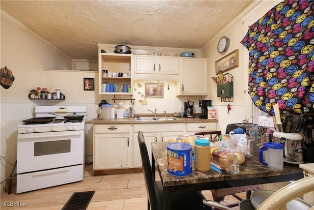 kitchen with white gas range, a textured ceiling, crown molding, sink, and light hardwood / wood-style flooring