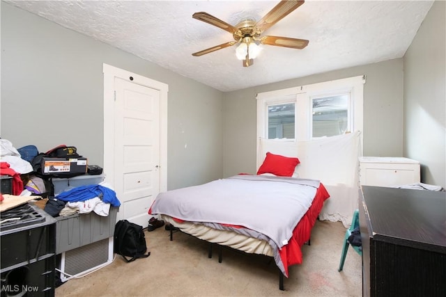 carpeted bedroom featuring ceiling fan and a textured ceiling