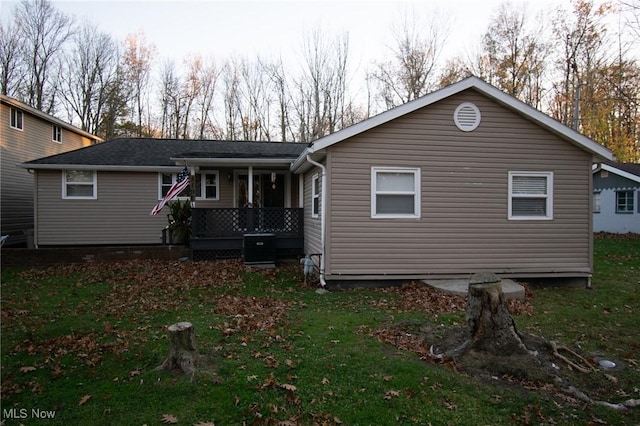 back of house with central air condition unit, a yard, and a porch