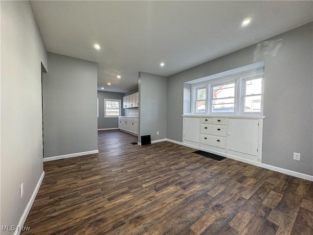 unfurnished room featuring a wealth of natural light and dark hardwood / wood-style flooring