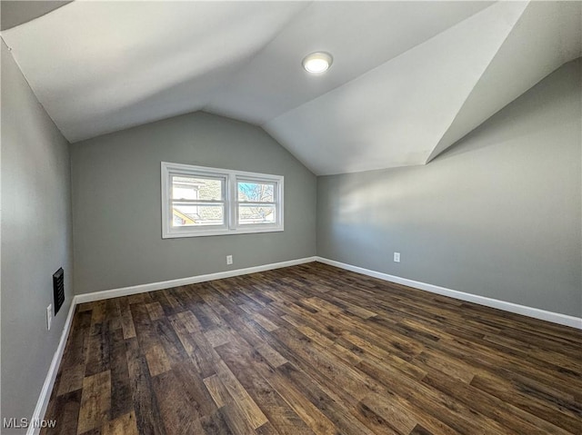 bonus room with dark wood-type flooring and vaulted ceiling