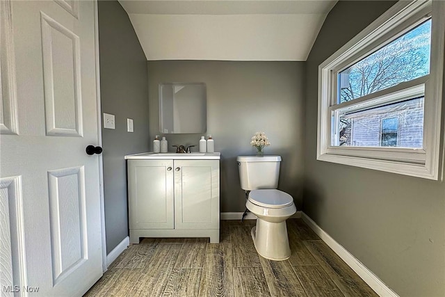 bathroom with vanity, wood-type flooring, lofted ceiling, and toilet