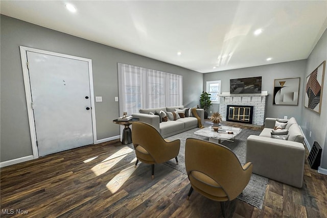 living room featuring a stone fireplace and dark hardwood / wood-style flooring