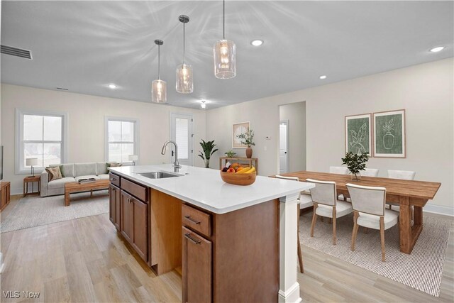 kitchen with pendant lighting, a center island with sink, light wood-type flooring, and sink