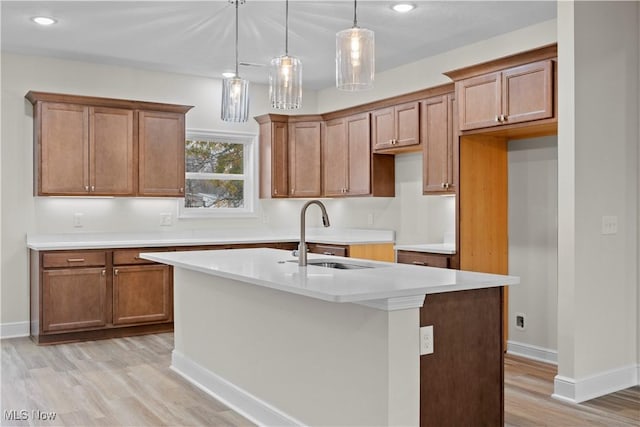 kitchen with pendant lighting, a center island with sink, light hardwood / wood-style floors, and sink