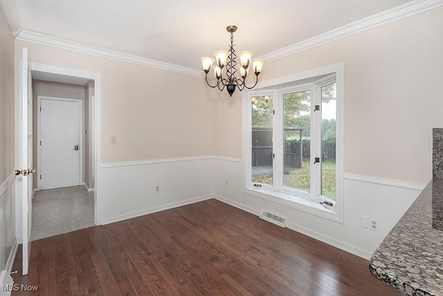 empty room with a notable chandelier, crown molding, and dark wood-type flooring