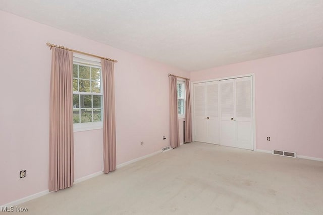 unfurnished bedroom with light carpet and a closet