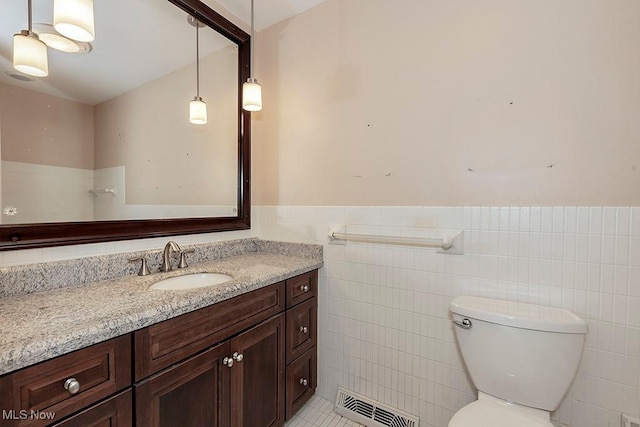 bathroom featuring tile patterned flooring, vanity, toilet, and tile walls