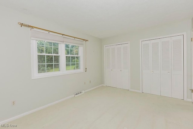 unfurnished bedroom with multiple closets and carpet