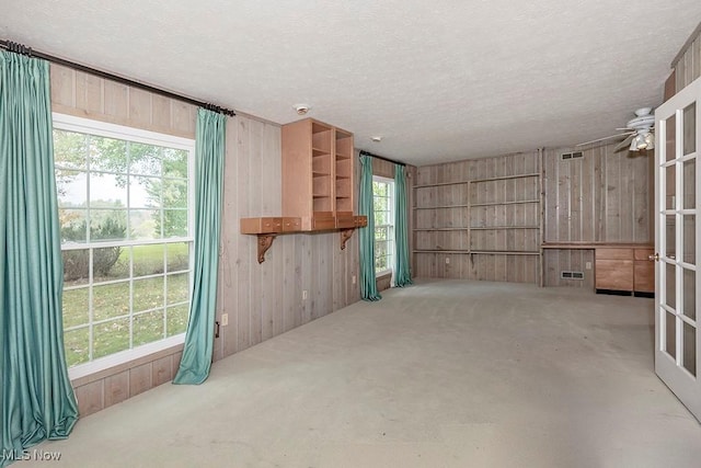 unfurnished living room with a textured ceiling and wooden walls