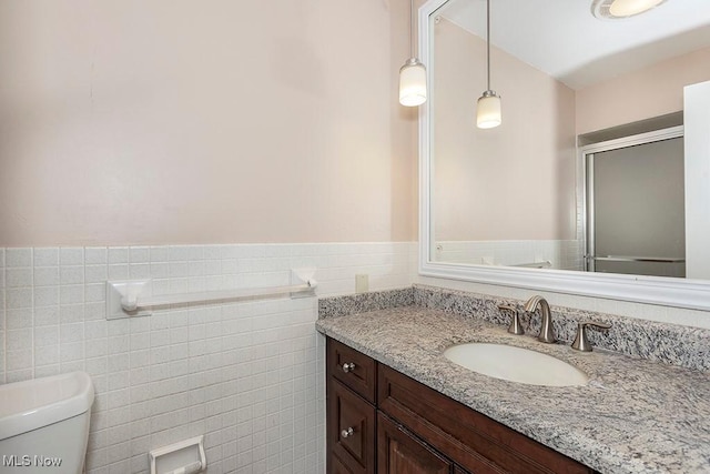 bathroom with vanity, toilet, and tile walls