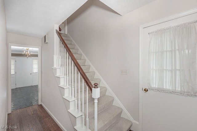 stairway with a chandelier and hardwood / wood-style flooring