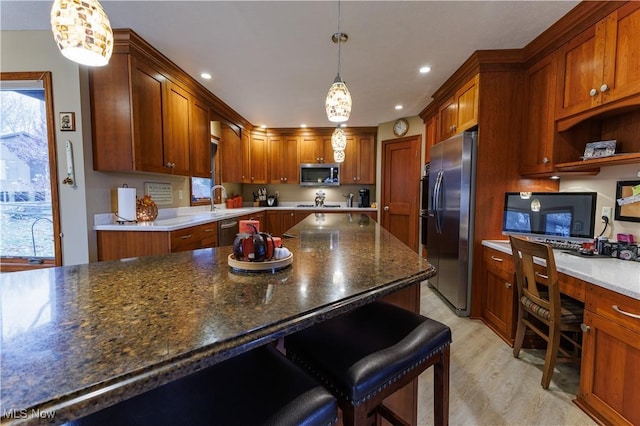 kitchen with a kitchen bar, dark stone counters, decorative light fixtures, and appliances with stainless steel finishes