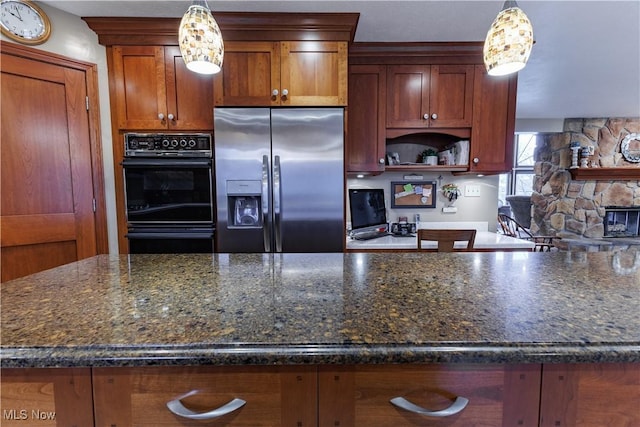 kitchen featuring stainless steel fridge, dark stone countertops, hanging light fixtures, and double oven