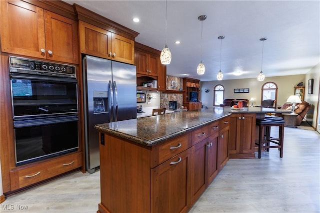 kitchen with stainless steel fridge with ice dispenser, a center island, light hardwood / wood-style floors, and double oven