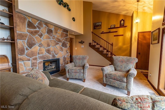 living room featuring lofted ceiling, a stone fireplace, carpet floors, and an inviting chandelier