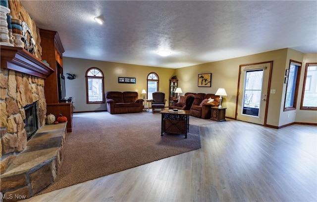 living room with hardwood / wood-style flooring, plenty of natural light, a fireplace, and a textured ceiling