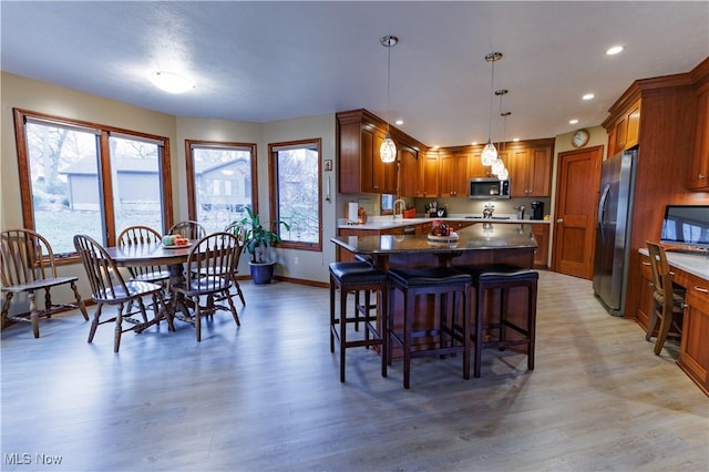 kitchen featuring pendant lighting, a kitchen island, stainless steel appliances, and light hardwood / wood-style floors