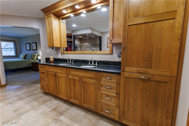 kitchen featuring dark stone countertops, sink, and light colored carpet