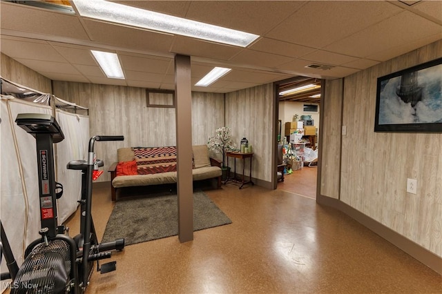 exercise area with wood walls and a drop ceiling