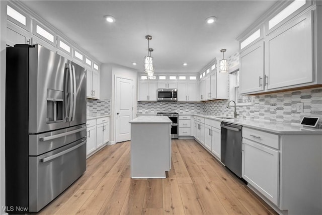 kitchen with a center island, white cabinetry, stainless steel appliances, and hanging light fixtures