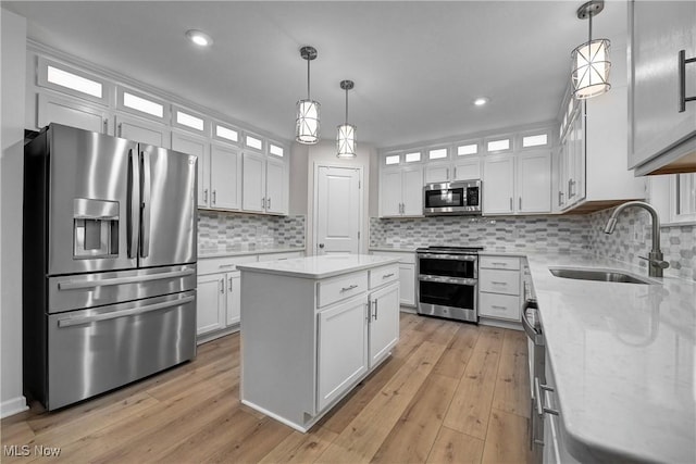 kitchen with a center island, sink, stainless steel appliances, pendant lighting, and white cabinets