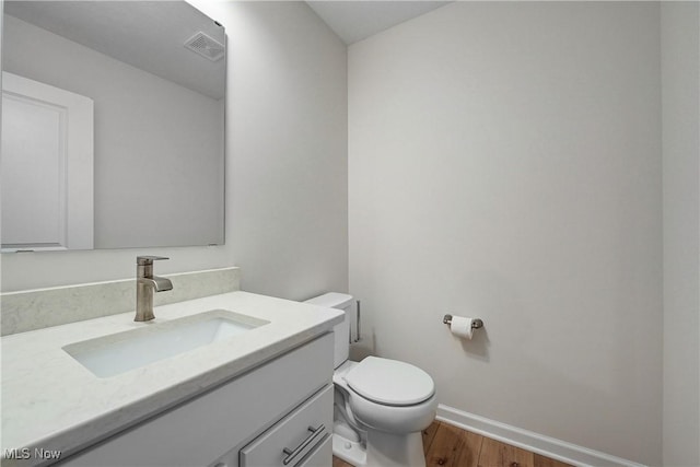 bathroom featuring vanity, hardwood / wood-style flooring, and toilet