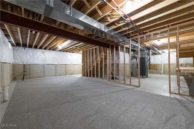 basement featuring brick wall and heating unit