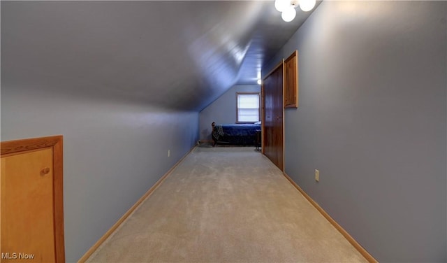 corridor with light carpet and vaulted ceiling