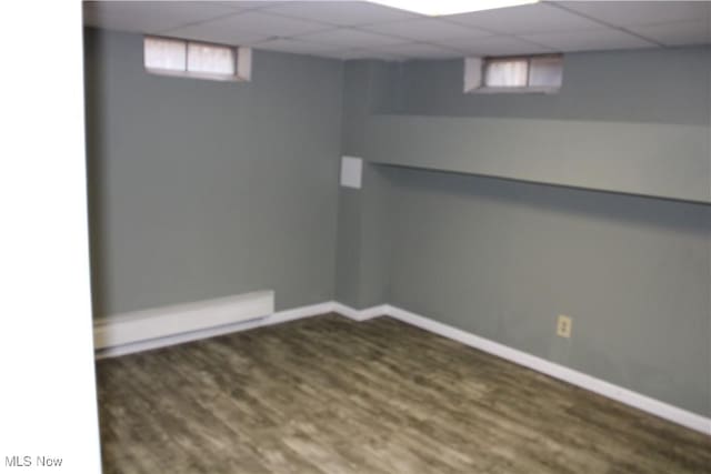 basement featuring dark hardwood / wood-style floors, a drop ceiling, and a healthy amount of sunlight