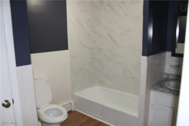 full bathroom featuring vanity, wood-type flooring, tile walls, washtub / shower combination, and toilet