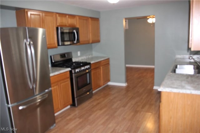 kitchen featuring ceiling fan, light hardwood / wood-style floors, sink, and stainless steel appliances