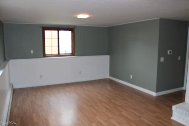 unfurnished room featuring hardwood / wood-style flooring, crown molding, and a baseboard radiator