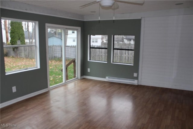 unfurnished room with baseboard heating, hardwood / wood-style floors, and a healthy amount of sunlight