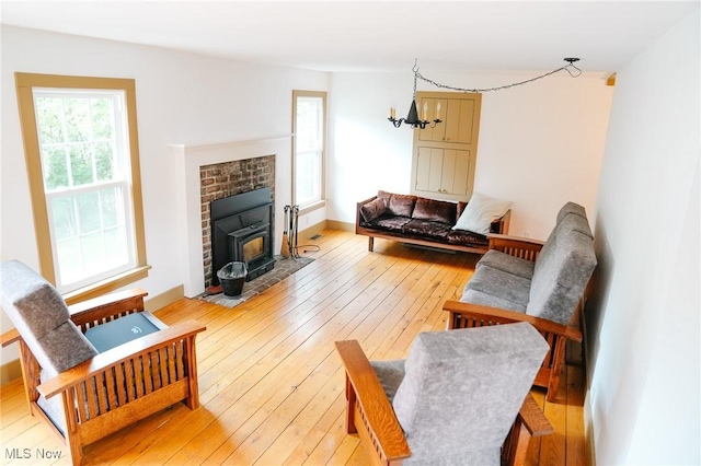 living room with light wood-type flooring, a wood stove, and a chandelier