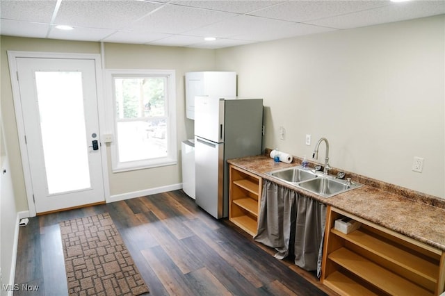 kitchen with stainless steel refrigerator, sink, dark wood-type flooring, and a drop ceiling