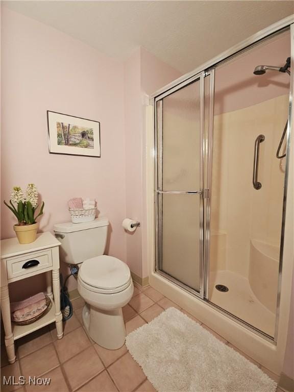 bathroom featuring tile patterned flooring, toilet, and an enclosed shower