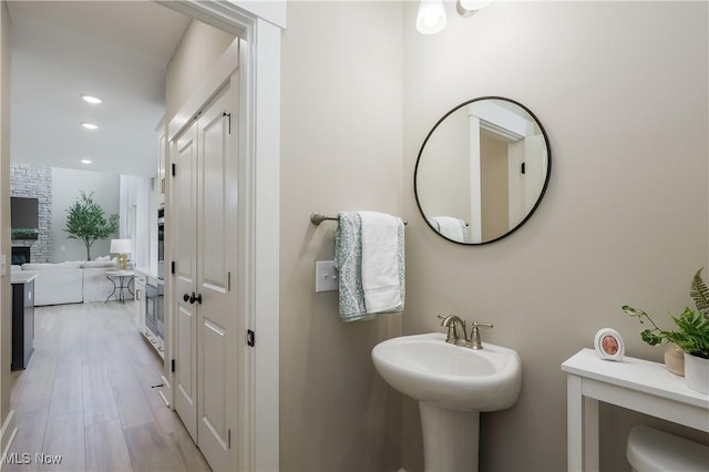 bathroom with a stone fireplace, sink, and wood-type flooring