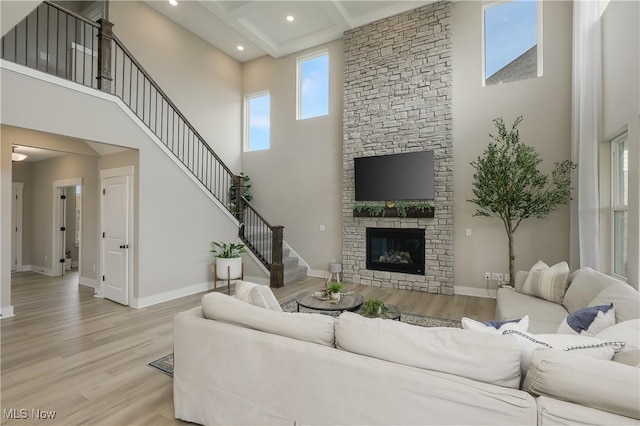 living room featuring plenty of natural light, light wood-type flooring, a fireplace, and a high ceiling