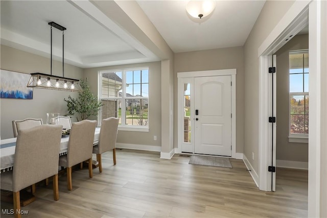 entryway with a tray ceiling and light hardwood / wood-style floors