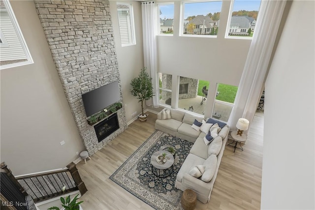 living room featuring light wood-type flooring and a stone fireplace