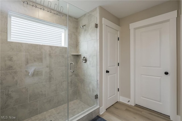 bathroom with a shower with shower door and hardwood / wood-style flooring