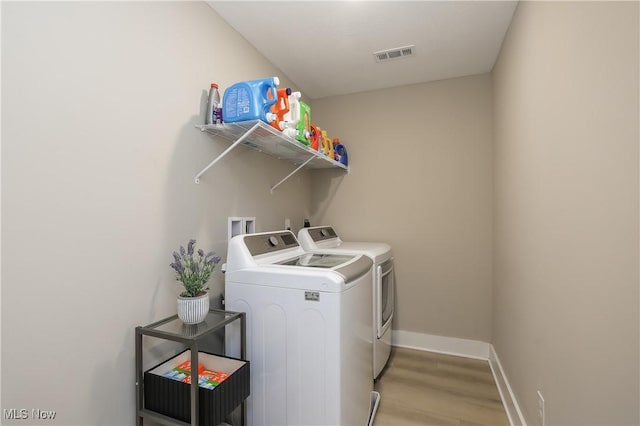 laundry area featuring washer and dryer and light hardwood / wood-style floors